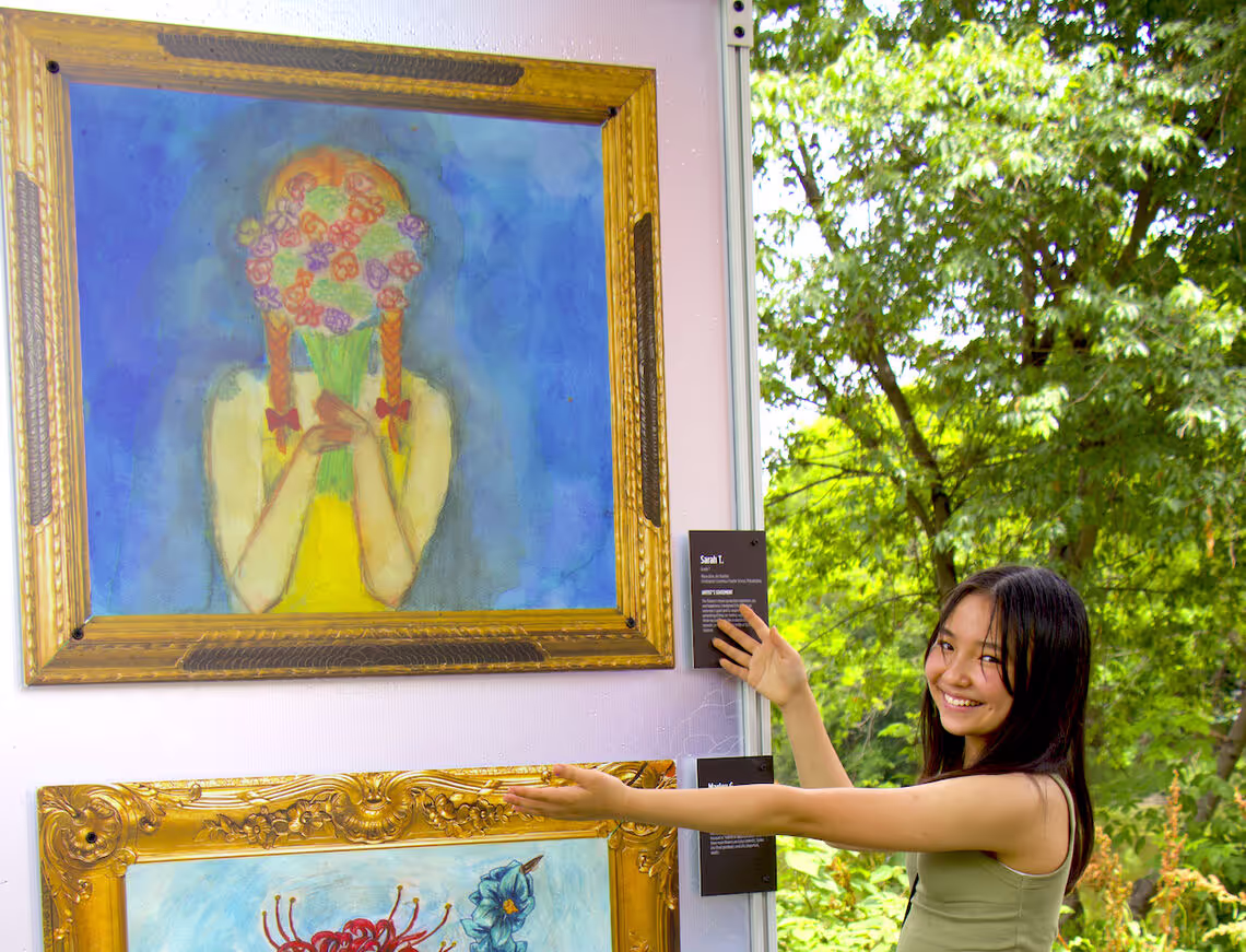 A woman standing next to a painting on a wall